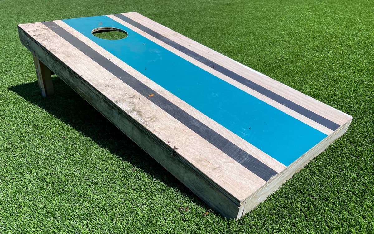 A striped custom cornhole board with the regulation 6 inch hole, set up on grass